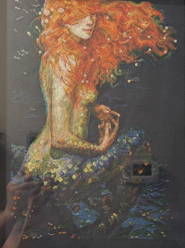 Cross stitch image of a mermaid with orange hair.