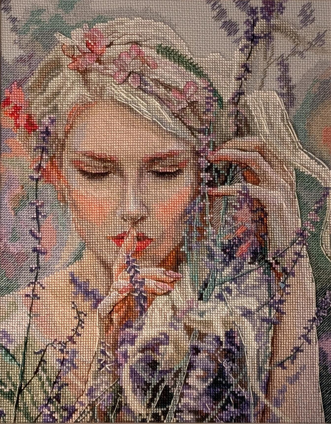 Cross stitch image of a light-skinned woman with white-blonde hair; she is shushing the viewer and holding flowers.
