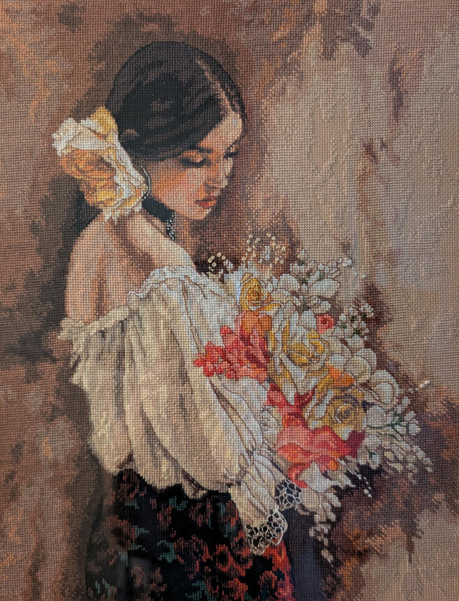 Cross stitch image of a woman with dark hair holding a bouquet.
